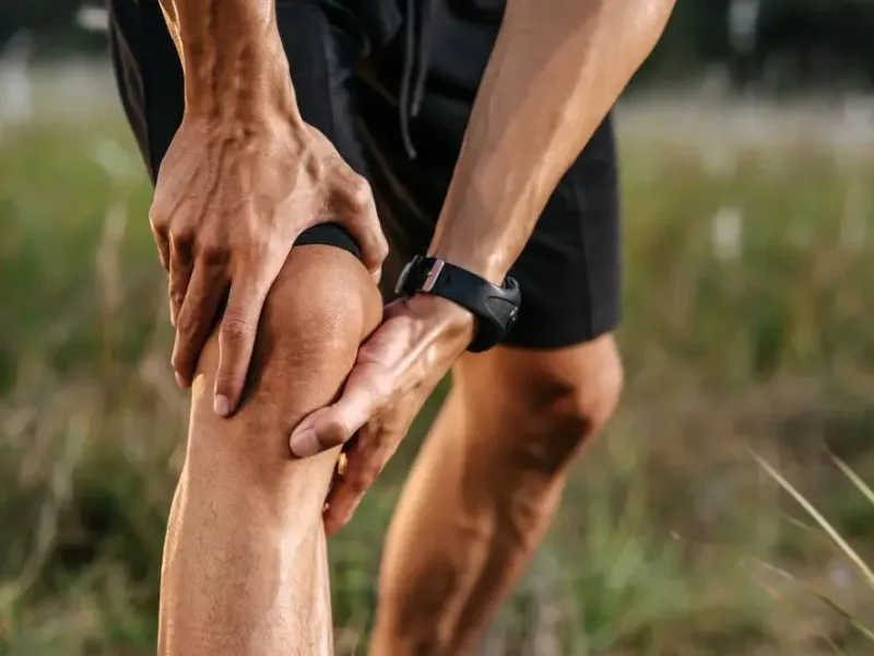 Runner holding a painful knee outdoors