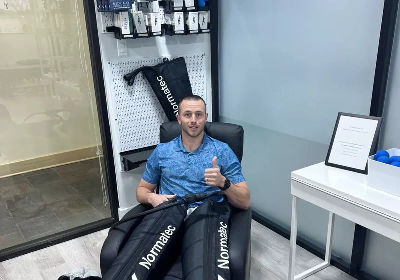 Patient seated with Normatec compression sleeves on both legs in the recovery room